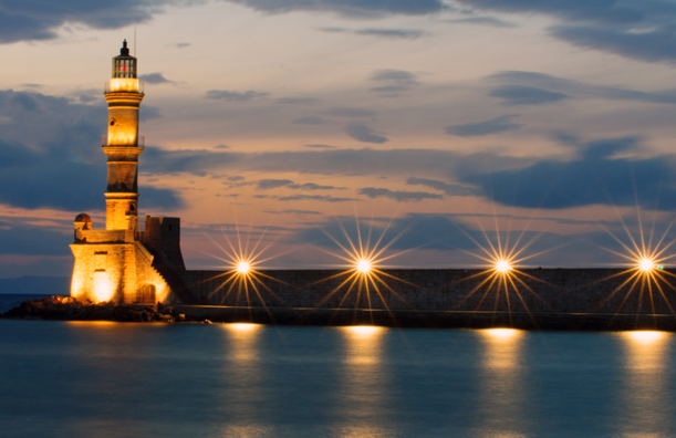 lighthouse at night with reflecting lights in water