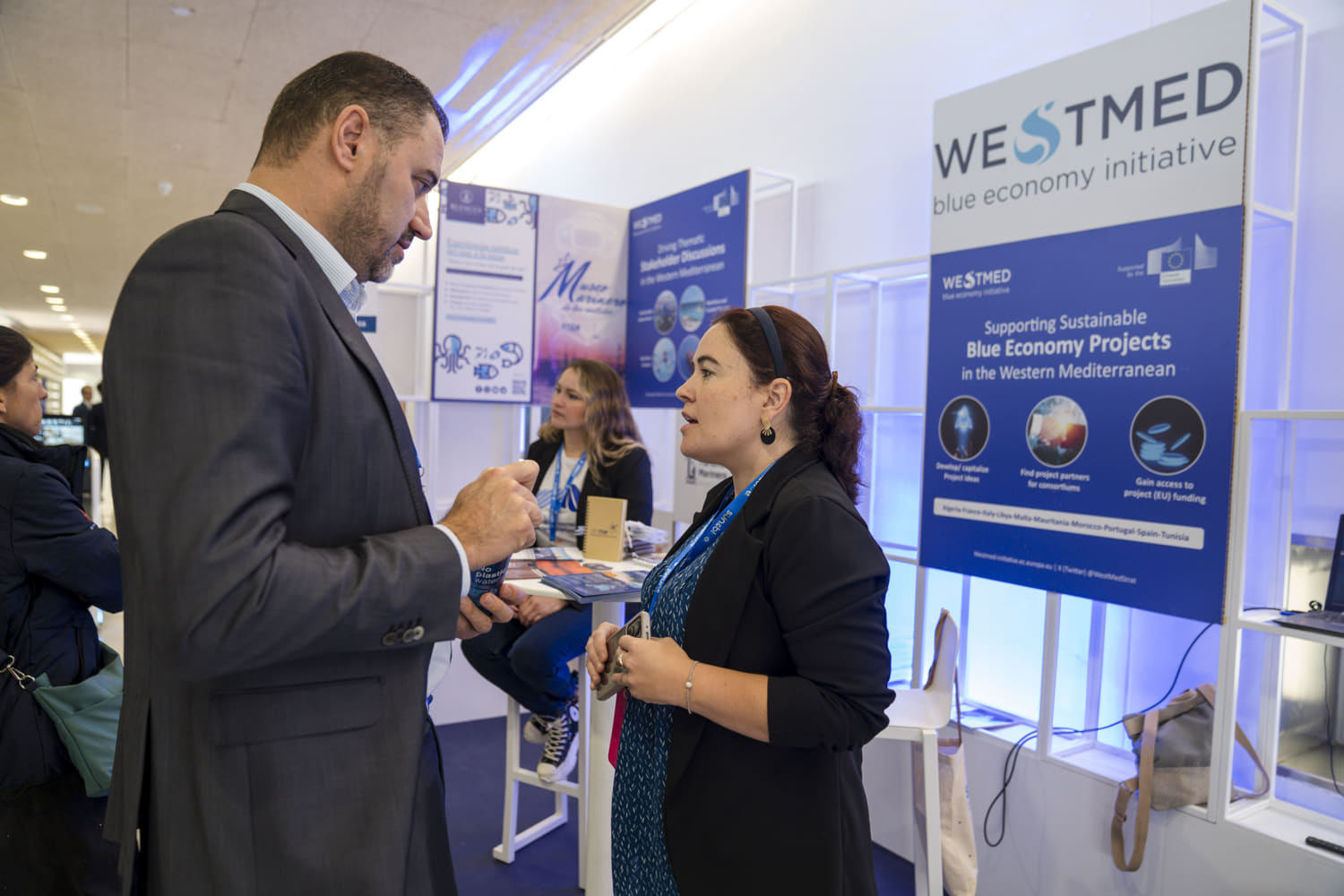 WestMED stand at Sun and Blue Congress 2023 with Marta Pascual talking to a visitor