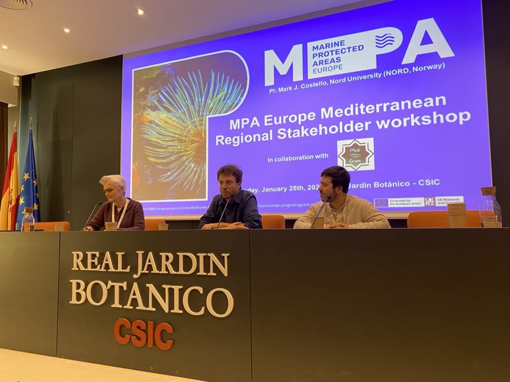 3 people sitting at elevated desk chairing the conference presenting