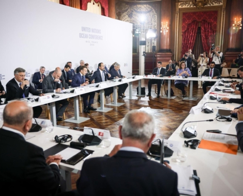 meeting with people seated at table against a United Nations Ocean Conference backdrop