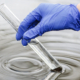 researcher holds test tube with water hand blue glove